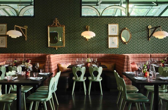 JouJou's French-California dining room with mint chairs, rose banquettes, ornate gold mirrors, patterned green walls, and elegantly set tables.