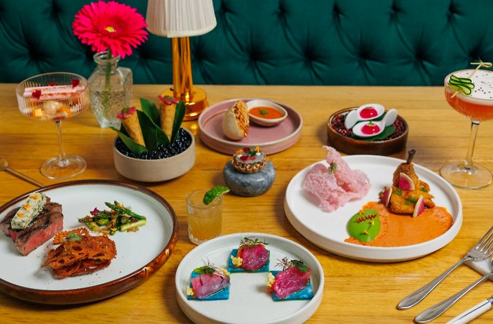 Colourful Royal Thai-inspired dishes and cocktails spread across a candlelit table at Kiin restaurant in Toronto.