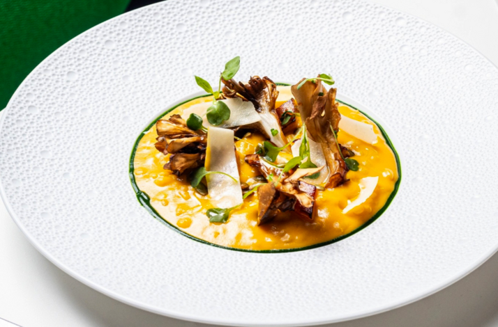 Golden risotto topped with roasted maitake mushrooms, shaved cheese, and microgreens at Le Jardinier Miami.