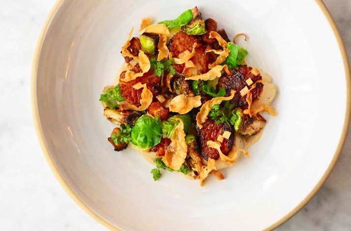 Roasted mushrooms and Brussels sprouts with crispy shallots and herbs, plated in a wide white bowl at Porto Boston.