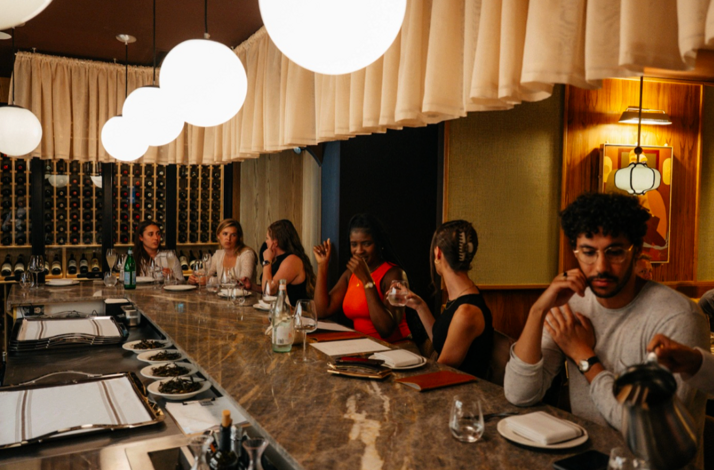 Guests seated at the marble bar counter under globe lights at Eloise.