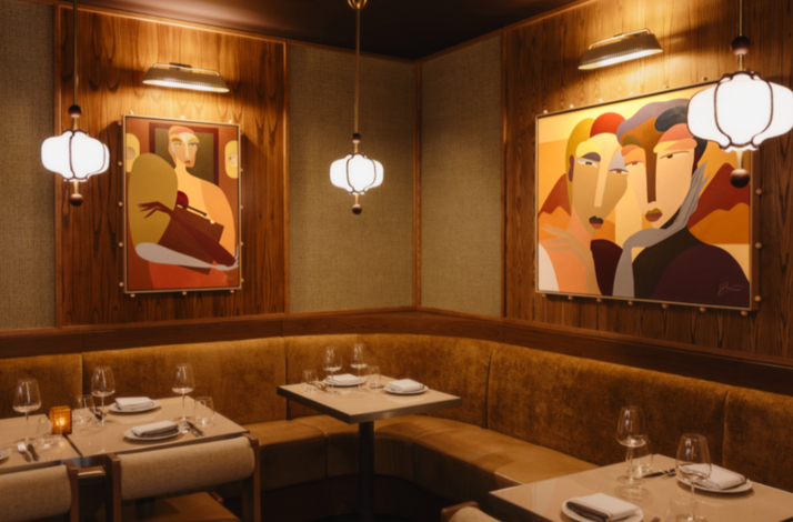 Corner banquette with framed artwork, wood walls, and neatly set tables at Eloise.