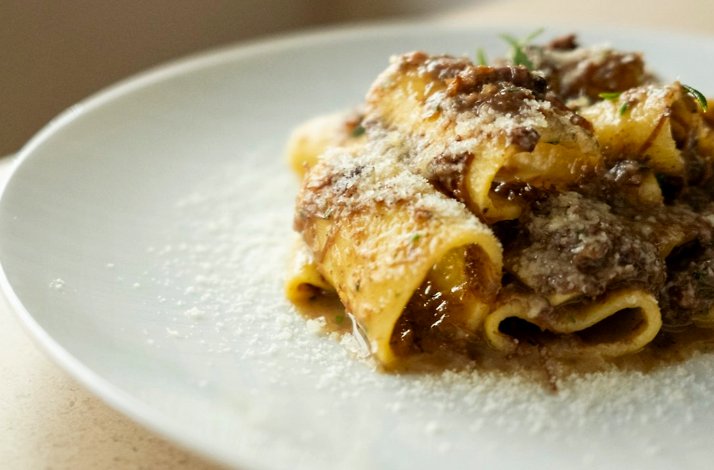 Wide ribbon pasta in rich meat ragu, dusted with finely grated Parmigiano, served at Osteria Giulia.