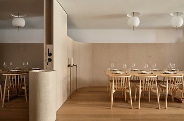 Osteria Giulia's private dining room with a long communal table, spindle chairs, and globe pendant lights.
