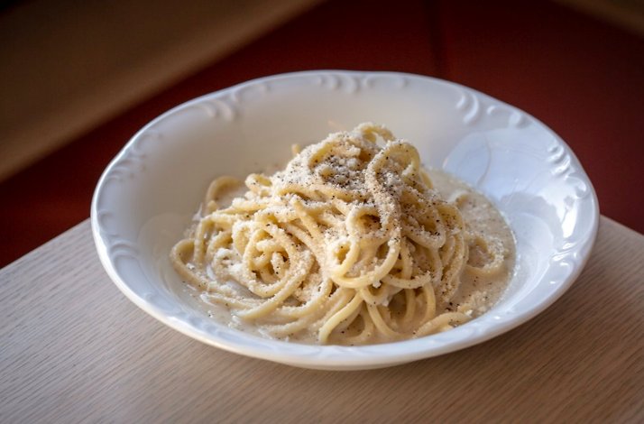 Creamy cacio e pepe spaghetti at Giuletta in a white bowl with cracked black pepper.