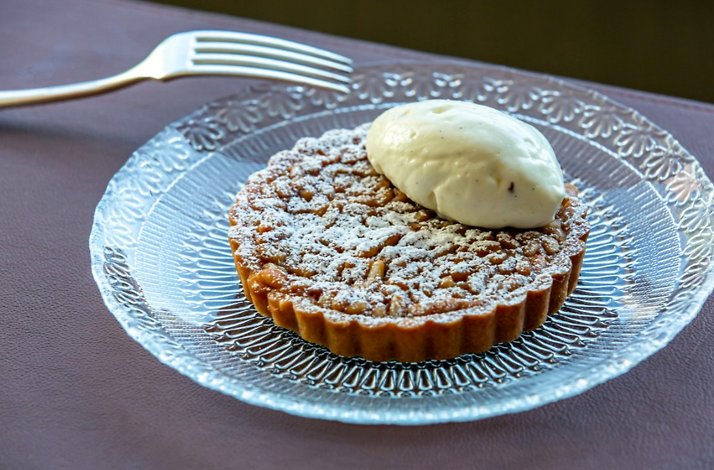 Powdered sugar tart at Giuletta served on a glass plate with a quenelle of vanilla cream.