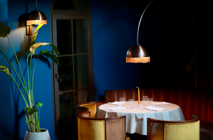 Elegant dining table at The Red Balloon with blue walls and warm pendant lighting.