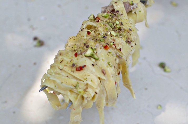 Fresh pasta swirled on a carving fork, topped with chopped pistachios and red pepper flakes at Dublin Cookery School.