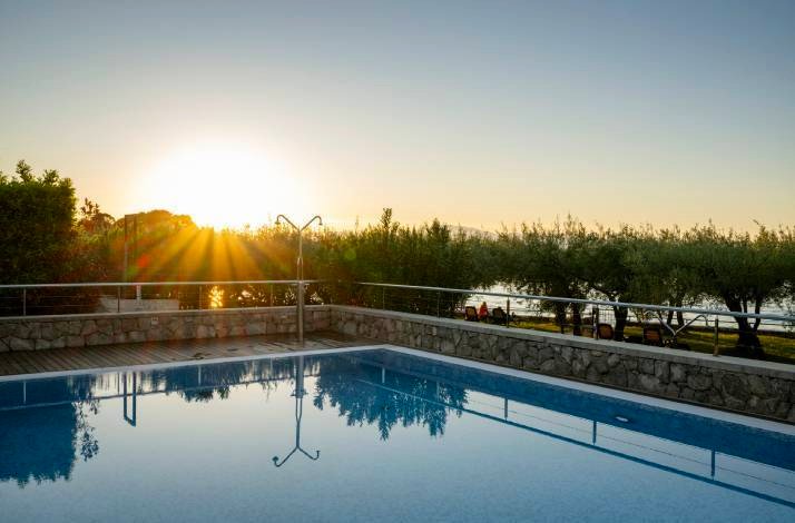 The outdoor swimming pool at Hotel Vila Rova in Malinska, Croatia, reflecting the sunset over the Adriatic Sea.