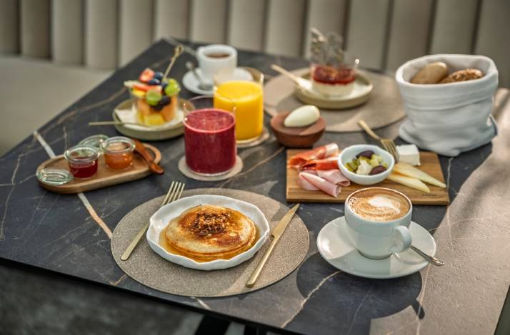 Breakfast table set for two people with fresh juice, fruit and coffee at Hotel Vila Rova.