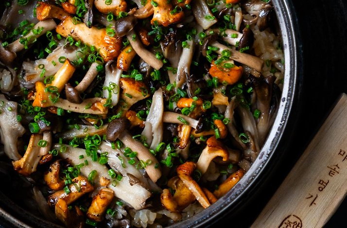 Stone pot rice topped with sauteed mixed mushrooms and sliced green onions, served in a traditional Korean dolsot.