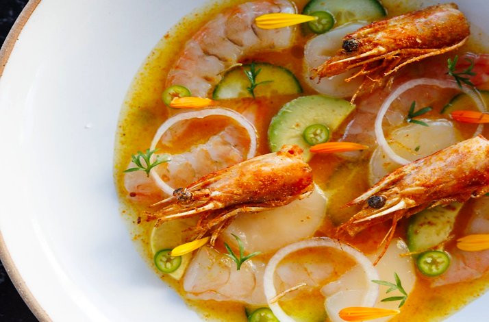Seafood aguachile with shrimp, cucumber slices, onion rings, and sliced chiles in a citrusy golden broth at Maria Isabel.