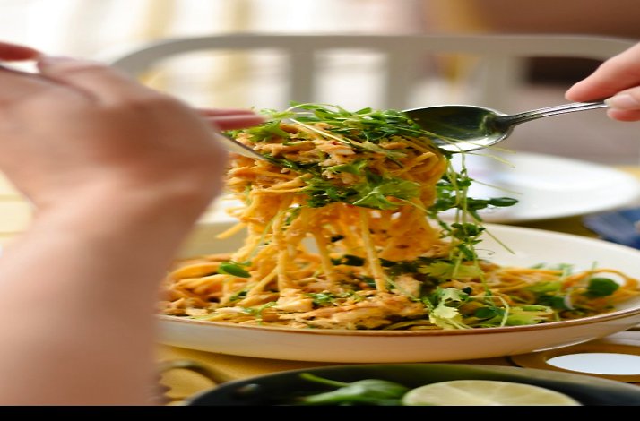 Fork twirling a mound of fresh pasta topped with herbs in a white bowl served at L’Oca d’Oro.