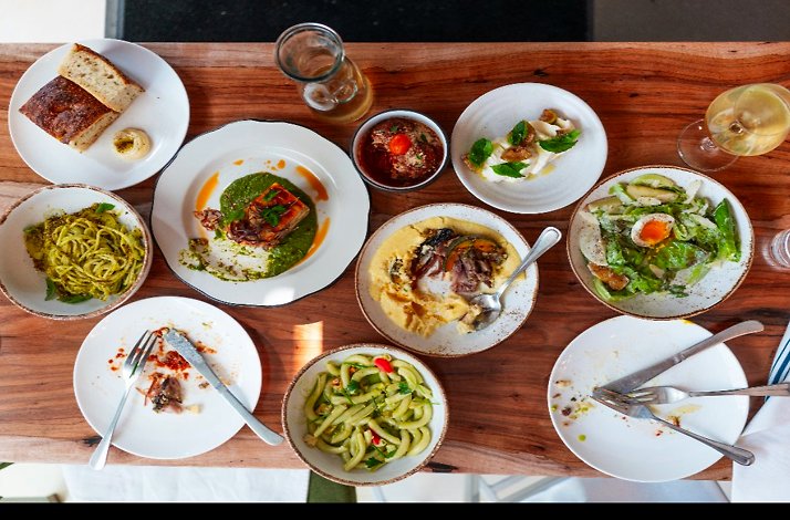 Overhead view of a shared Italian-style meal with pasta, salad, small plates, and wine at L’Oca d’Oro.