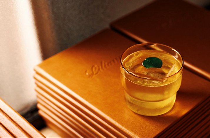 A glass of drink put on the pile Menus of Liliana restaurant.