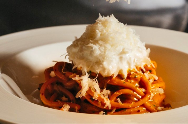 A close-up photo of a pasta in plate with grated parmesan cheese.
